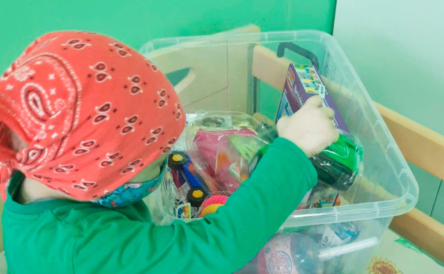 Ребенок в онкоцентре с коробкой игрушек