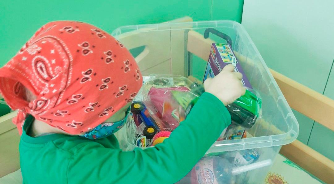 Ребенок в онкоцентре с коробкой игрушек